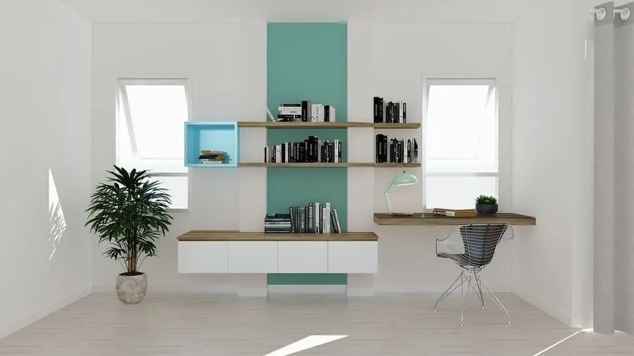 Sala blanca y luminosa con una pared verde agua, estanterías, escritorio y una planta
