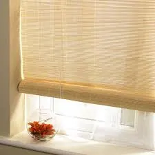 Estor enrollable de bambú medio recogido sobre una ventana con un jarrón de flores en el alféizar