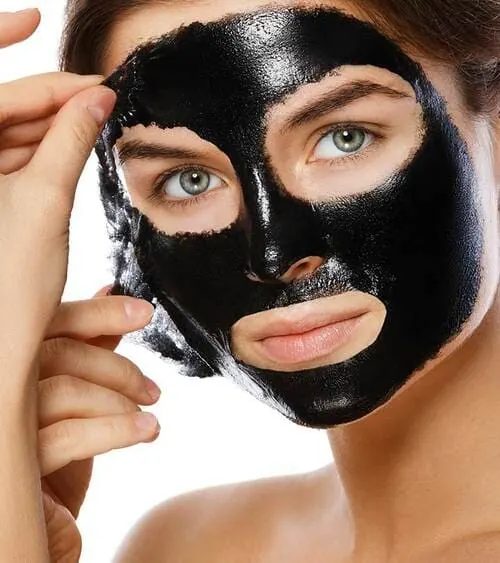 Mujer retirando una mascarilla negra de carbón de bambú de la cara